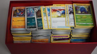 une boîte rouge remplie de nombreuses cartes, posée sur une table