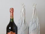 two bottles of champagne sitting on top of a wooden table next to a bottle of wine