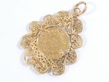 a gold coin in the center of a gold pendant