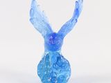 blue glass figurine of a bird sitting on top of a white surface