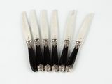 four knives are lined up on top of each other on a white surface