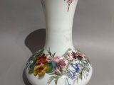 un vase blanc orné de fleurs peintes, posé sur une table