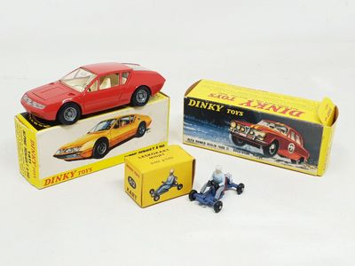 deux petites voitures et une boîte de jouets posées sur une surface blanche