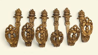 cinq poignées de porte en laiton ouvragées sur une surface blanche