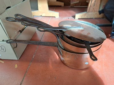 des casseroles et des poêles sont posées par terre devant un carton