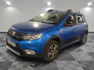 La Dacia bleue est garée dans une pièce au sol carrelé en damier.