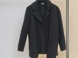 coat hanging on a clothes rack in front of a white wall