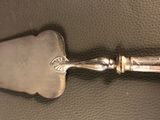 a silver spoon with a handle sitting on a leather surface