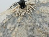a close up of a white lace umbrella with a black button