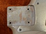 a close up of a silver guitar with a rusted body