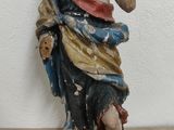 une statue de Jésus assis sur un plancher en bois, près d'un mur