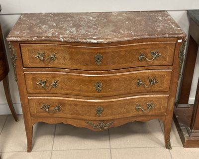 une commode au plateau en marbre, à côté d'un fauteuil