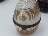 a glass egg sitting on a table next to other glass vases