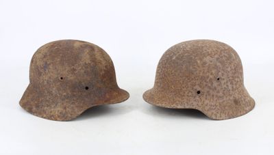 pair of wwii era german helmets with holes on the side
