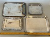 four silver trays and a measuring ruler on a table