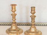 une paire de bougeoirs anciens en laiton posés sur une table dans une pièce