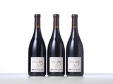 three bottles of red wine are lined up on a table