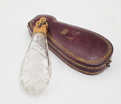 une bouteille en verre et un étui en cuir posés sur une surface blanche