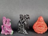 three small figurines of asian people are sitting on a table