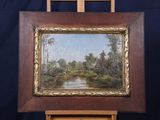 an oil painting of a river and trees in a wooden frame