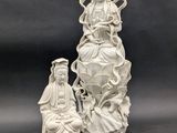 une statue blanche représentant une femme assise sur un rocher, à côté d'une autre statue représentant une femme