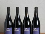 quatre bouteilles de vin sont alignées sur une table en bois