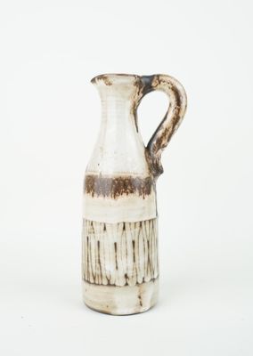 a white vase with a brown handle on a white surface