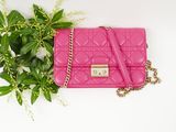 pink quilted purse with chain and flowers on a white background