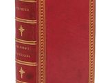un vieux livre rouge aux tranches dorées, avec une croix sur la couverture