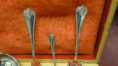 trois cuillères en argent dans un coffret en bois posé sur une table