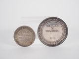 a silver coin sitting next to a silver coin on top of a white surface