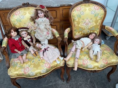 three dolls sitting on the chairs in the room