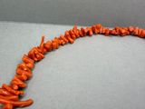 un gros plan sur un collier composé de perles de corail orange