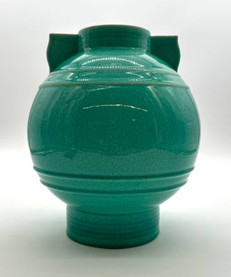 a green vase that is sitting on a white surface