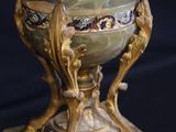 a green vase with a gold base on a black background