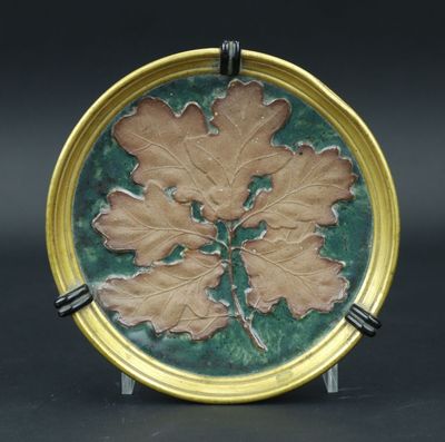 une assiette verte et dorée ornée d'un motif de feuilles