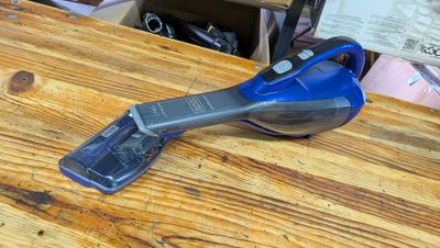 un aspirateur à fil bleu et noir posé sur une table en bois