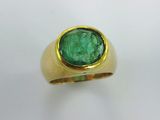 a close up of a gold ring with a green stone