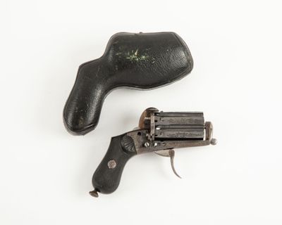 un vieux revolver et un étui en cuir posés sur une surface blanche