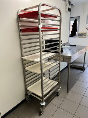 une étagère métallique sur laquelle sont disposés de nombreux plateaux de nourriture