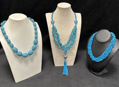 three necklaces with blue beads and a tassel on display