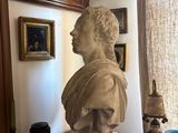 a bust of a man sitting on a table in front of a window