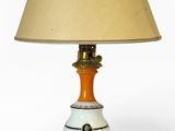 une lampe orange et blanche posée sur une table, à côté d'un abat-jour