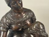 bronze statue of a woman holding a child and a dog