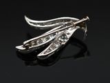 a close up of a silver broochle with a leaf shaped broochle on it