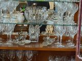 un homme debout derrière une vitrine remplie de verres à vin