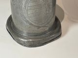 a silver vase with a design on it on a white surface