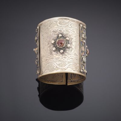 an antique silver bracelet with a red stone in the center