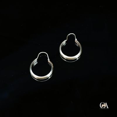 une paire de boucles d'oreilles créoles en argent sur fond noir