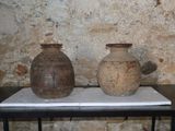 deux vases posés sur une table devant un mur de pierre